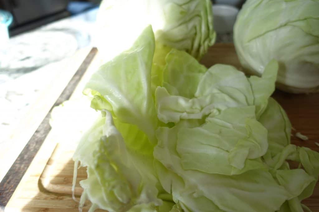 cabbage pieces and heads of cabbage on a wooden cutting board