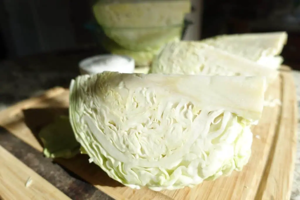 cabbage quartered lying on a wooden cutting board