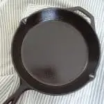 well seasoned cast iron skillet over top an apron