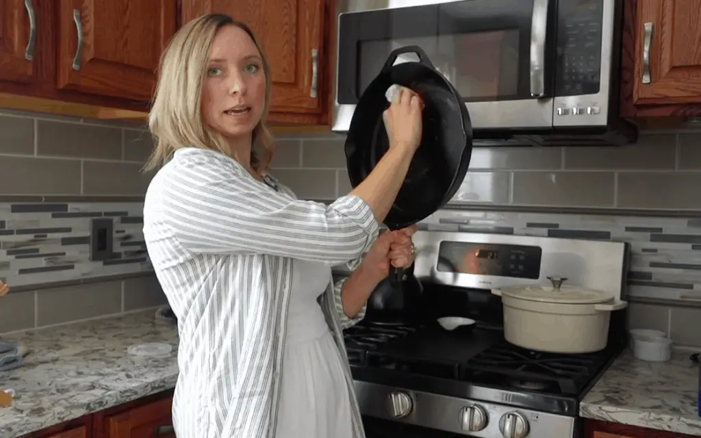 woman showing how to season a cast iron skillet with coconut oil