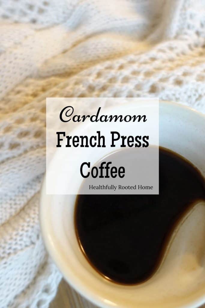 Cardamom french press coffee fall coffee drink in a white ceramic coffee mug on top of a cozy white sweater