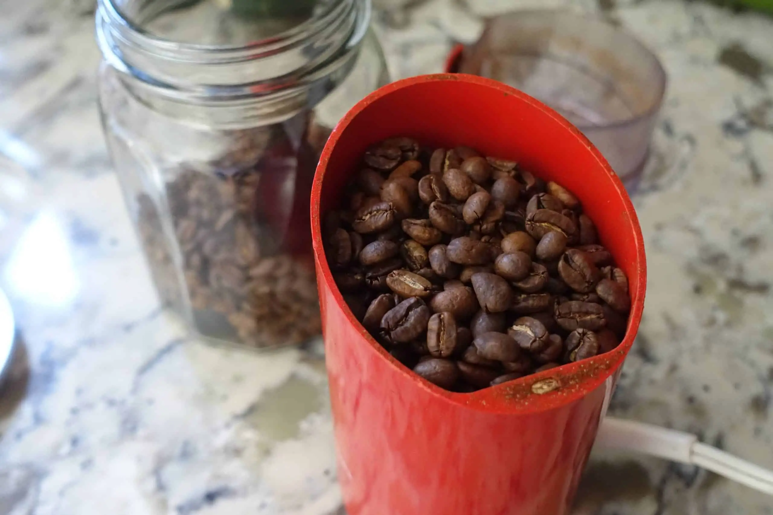 coffee beans inside red coffee grinder