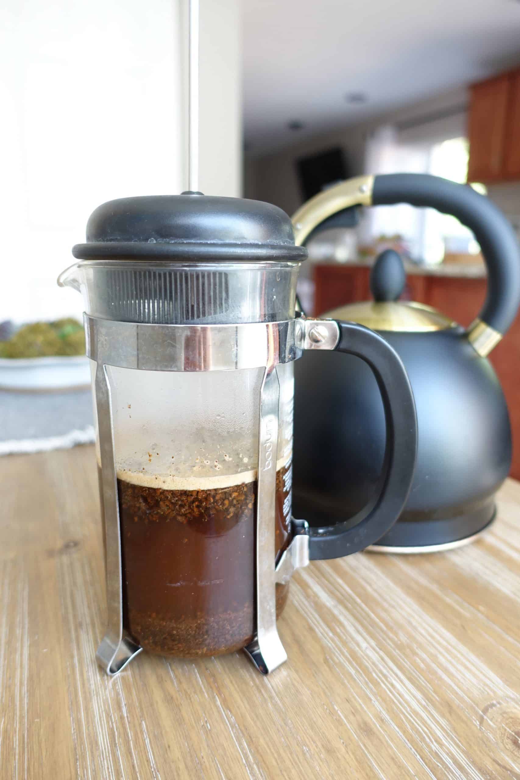 coffee steeping in a french press with tea kettle in the back