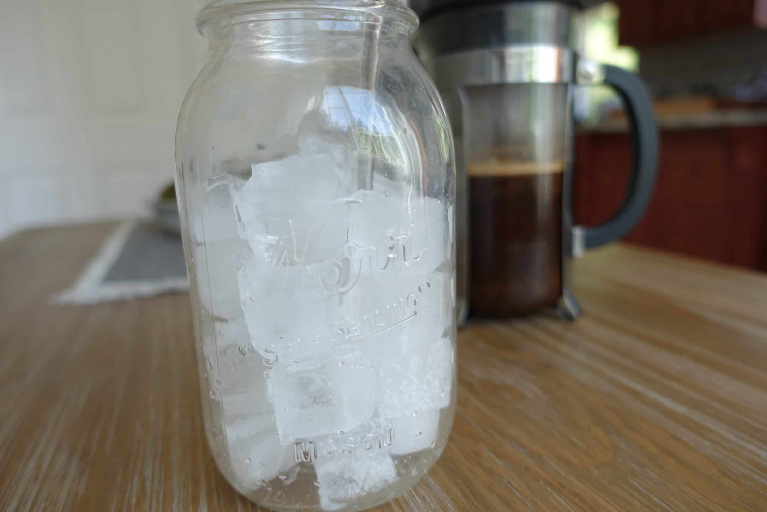 large mason jar full of ice with french press in the back