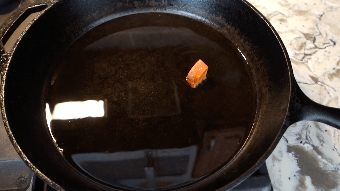 testing the oil in cast iron skillet by tossing one sweet potato in the skillet to see if it sizzles