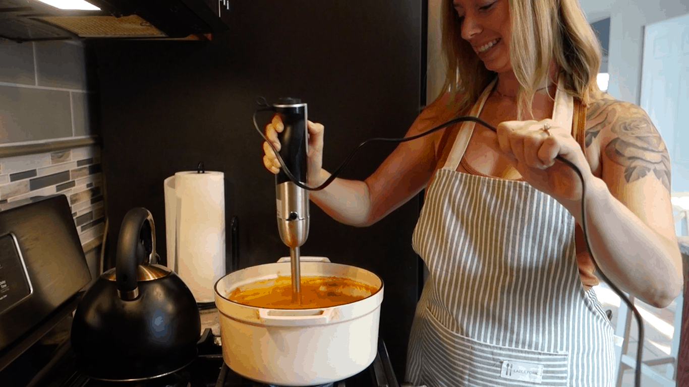 using an immersion blender to blend heart healthy chili inside of a white dutch oven