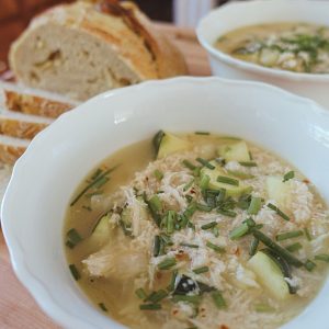 lemon chicken gnocchi soup with chives on top and roasted garlic sourdough bread