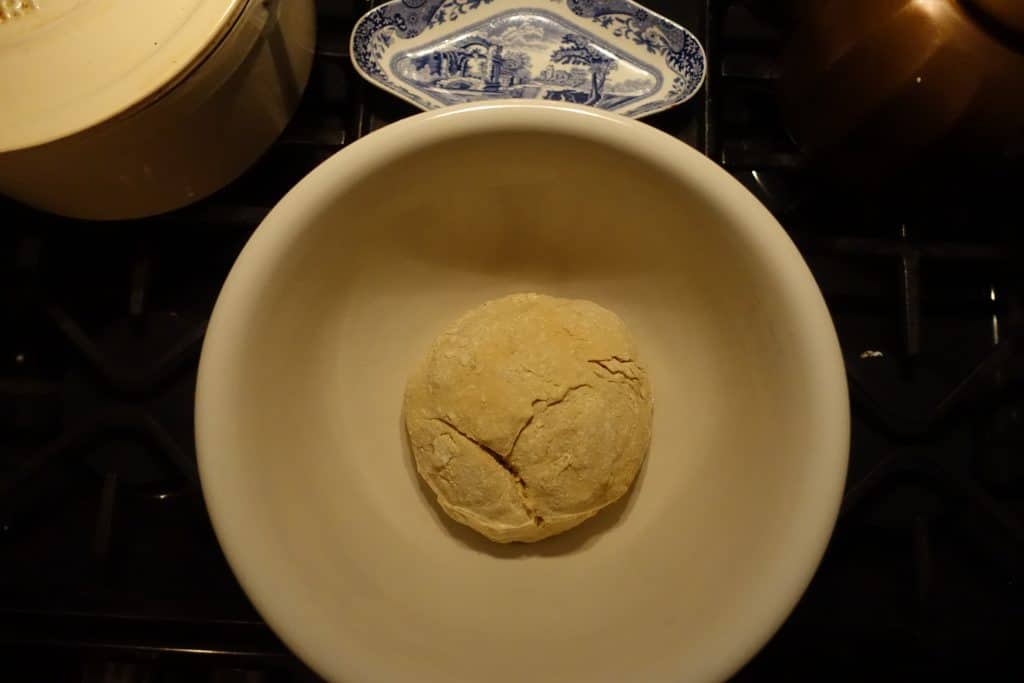 sourdough bagel dough fermenting on counter in a ceramic bowl with blue china in background