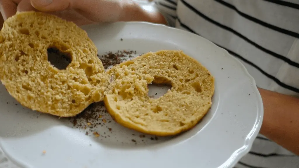 sliced open homemade zaatar bagel on a white plate with a perfectly crumby inside