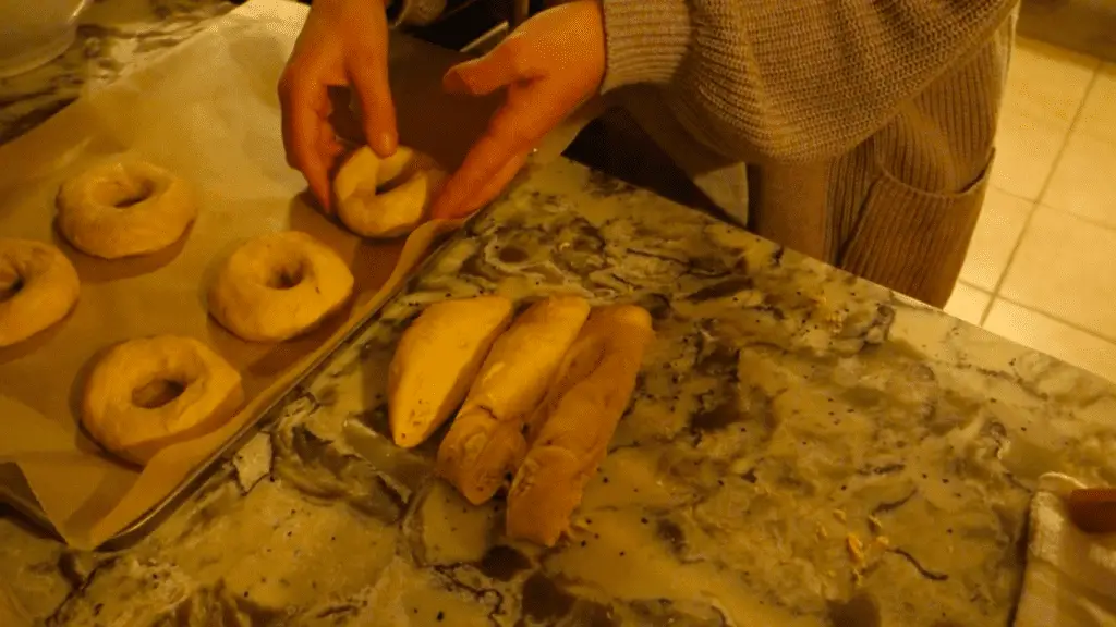 placing shaped sourdough bagel dough on parchment lined baking sheet