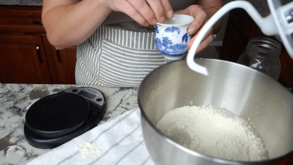 adding salt to the bowl of a kitchenaid stand mixer