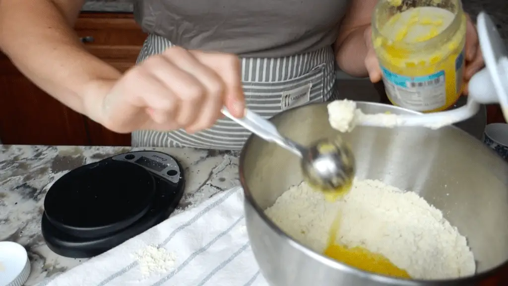 adding ghee to the bowl of a kitchenaid stand mixer to make einkorn tortillas