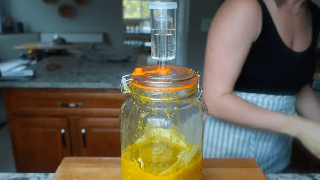 curry kraut in a fermenting jar with a weight overtop