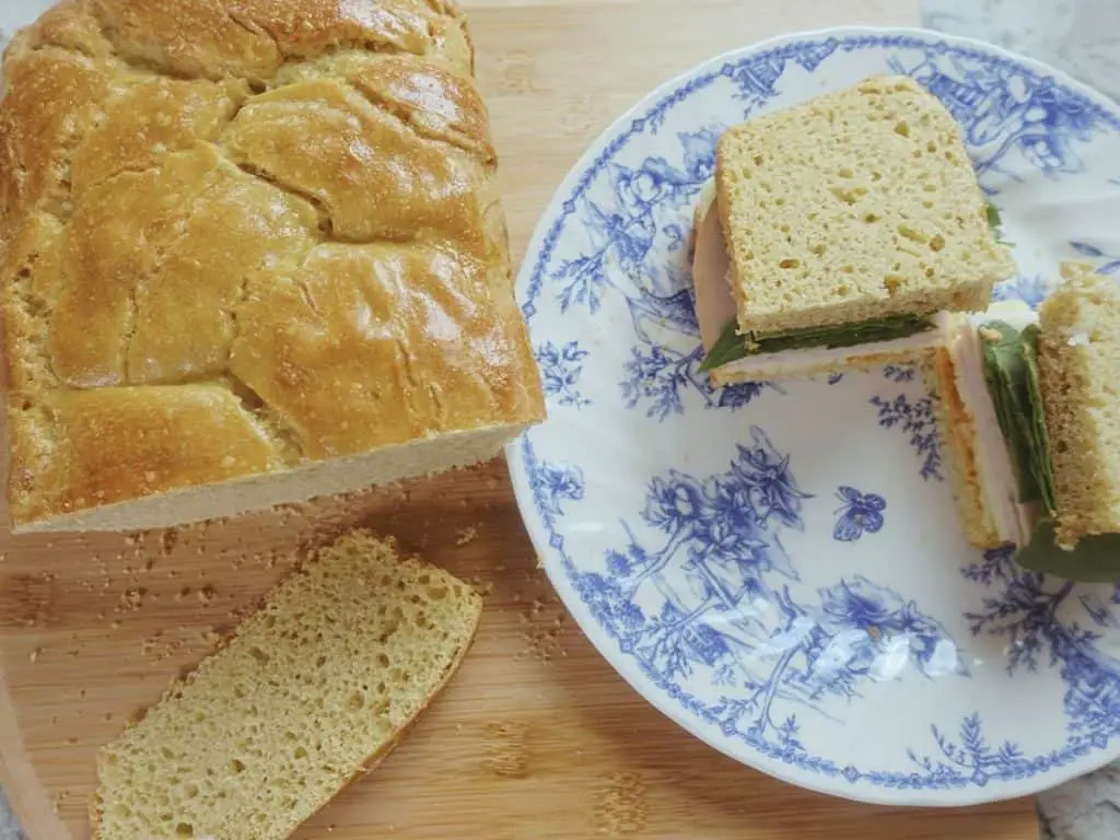 einkorn sourdough sandwich bread loaf next to a deli sandwich on a blue and white plate