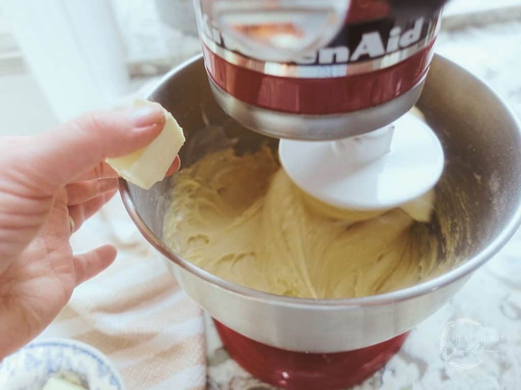 adding pads of butter to dough inside of a stand mixer