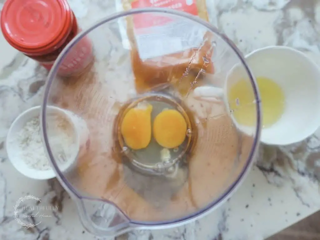 immersion blender cup with eggs inside and harissa paste and chili powder in the background