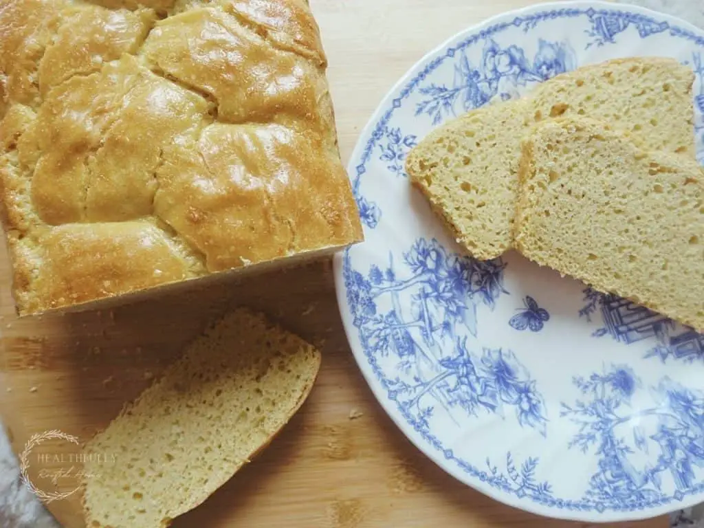 braided loaf of einkorn sourdough sandwich bread next to 2 slices on a blue and white plate