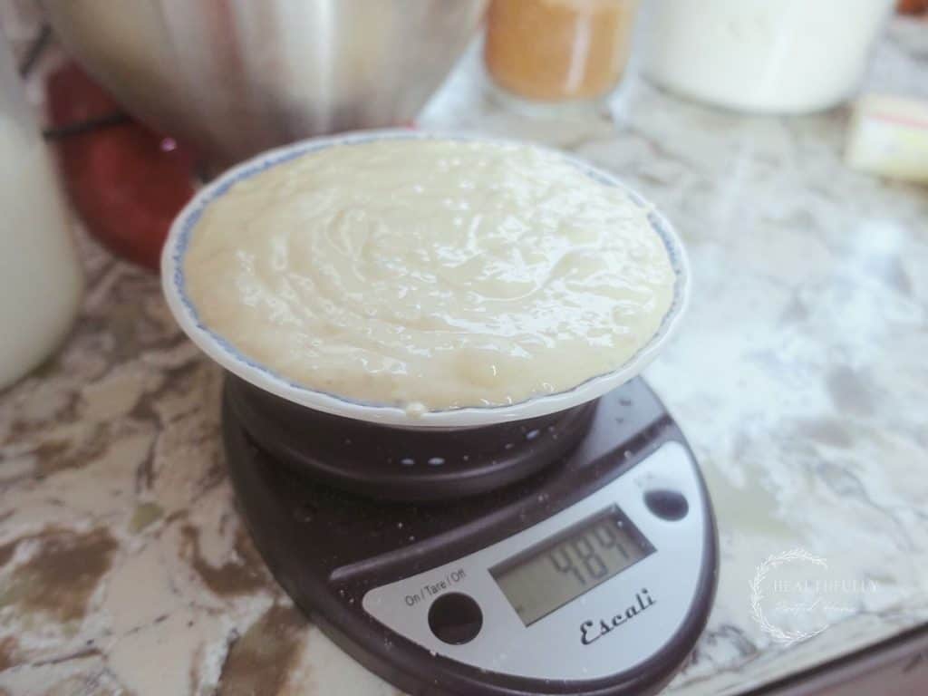 sourdough starter in a bowl being weighed on a black kitchen scale 