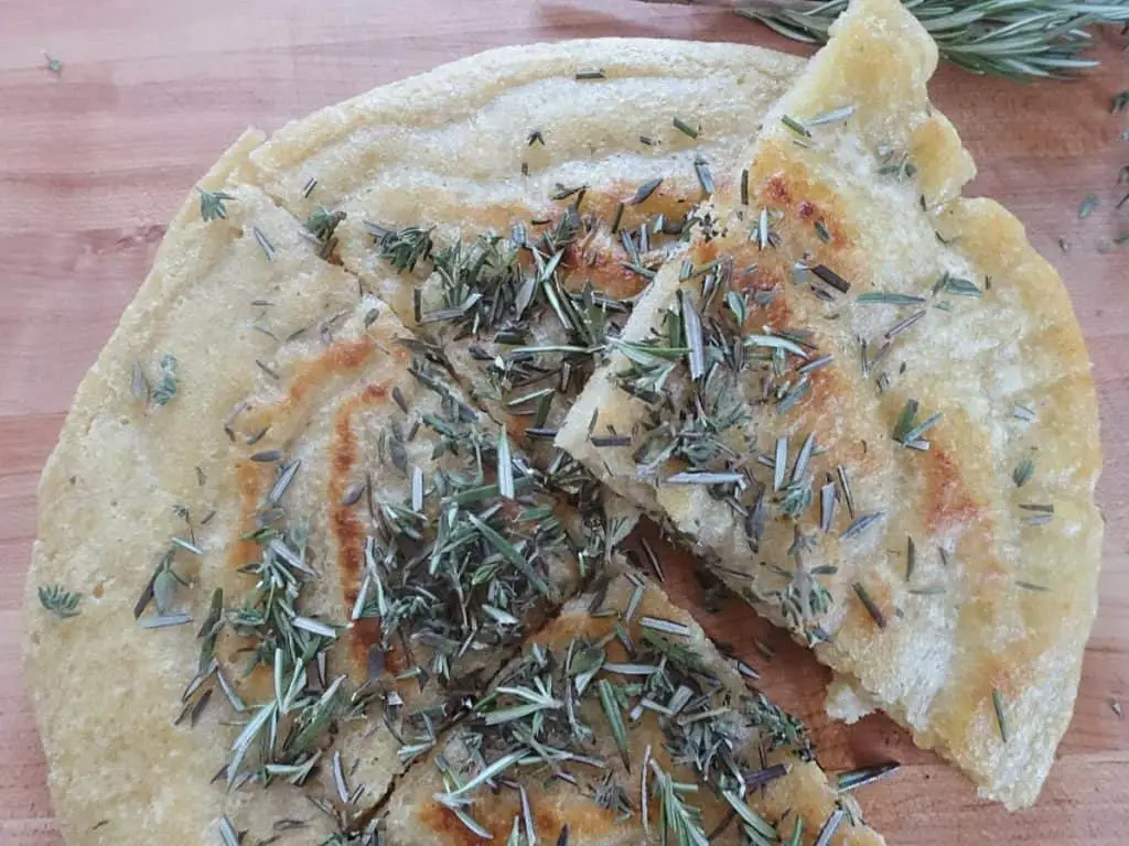 sourdough discard flatbread cut into triangles with rosemary and thyme on top 