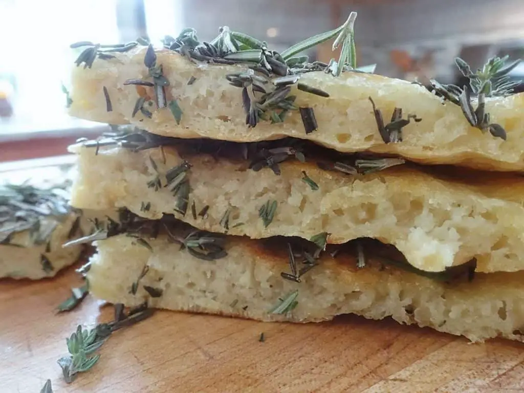 sourdough discard flatbread cut into triangles stacked  on top of eachother with fresh herbs