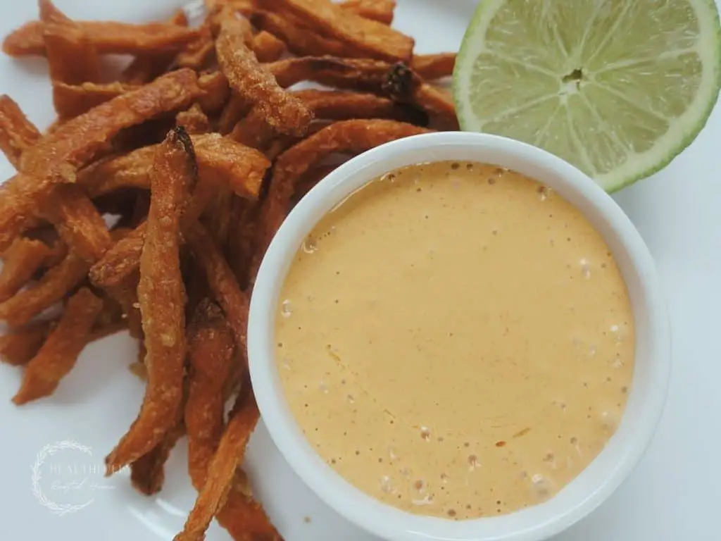 ancho aioli on a white plate with a lime and sweet potato fries