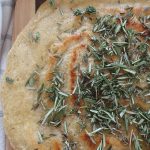sourdough discard flatbread with dried herbs on top next to a blue and white striped tea towel