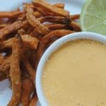 ancho aoili in a white dish with sweet potato fries and lime in the background