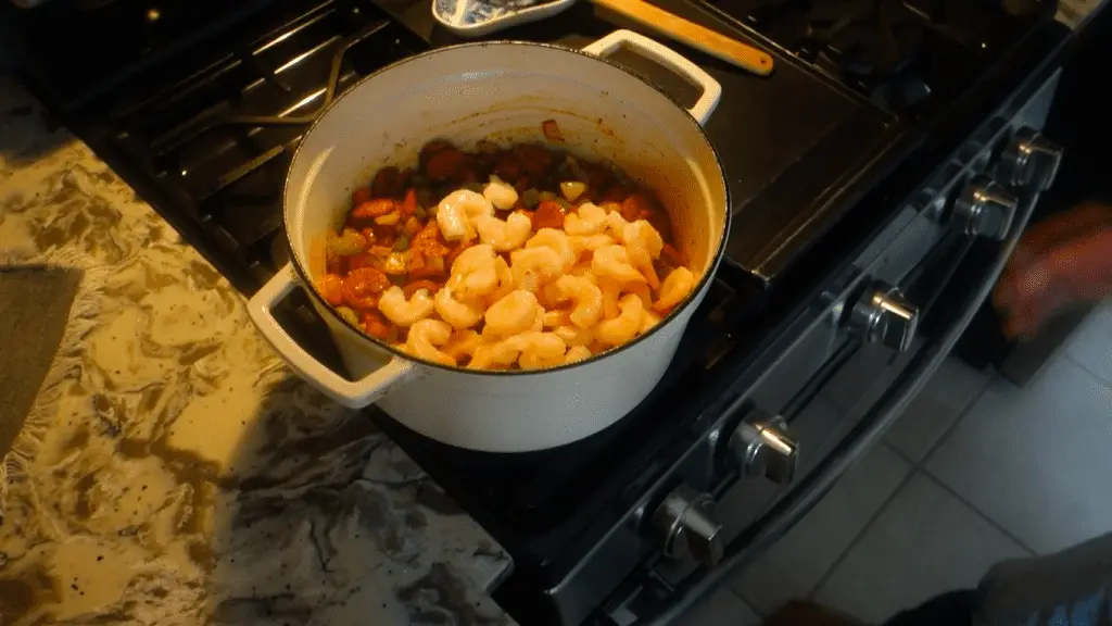 shrimp inside of a white dutch oven with sausage and veggies