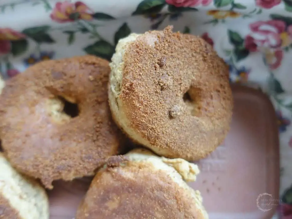 sourdough donuts with cinnamon sugar stacked on top eachother on a clay warmer with a floral liner