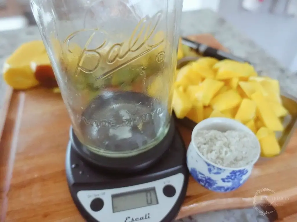 mason jar sitting on a kitchen scale with mangos and salt beside it