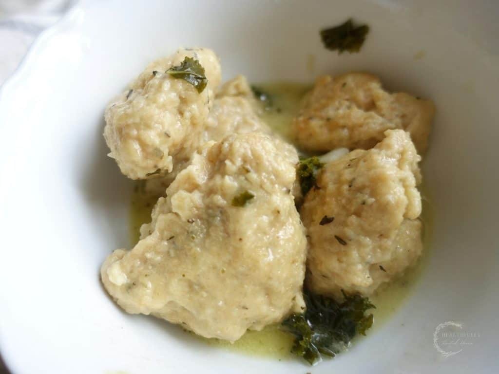 boiled sourdough drop dumplings in a white bowl with kale throughout