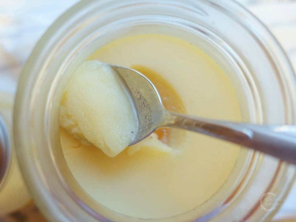 scraping the gelled fat off the chicken collagen soup inside of a mason jar with a spoon