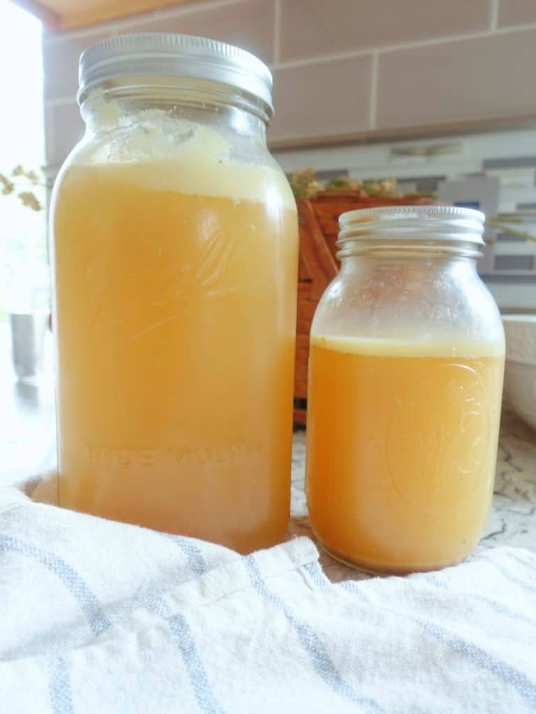 traditional cooking bone broth in mason jars with a white and blue striped tea towel in front
