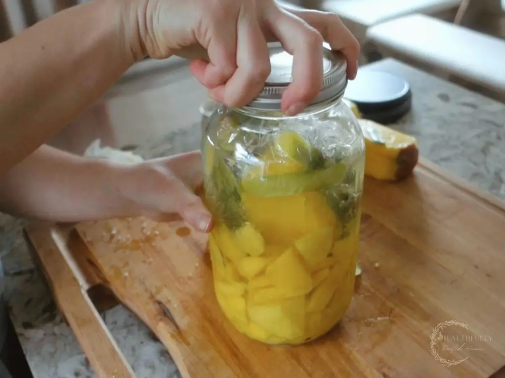 twisting on a lid of the mason jar to ferment fruit