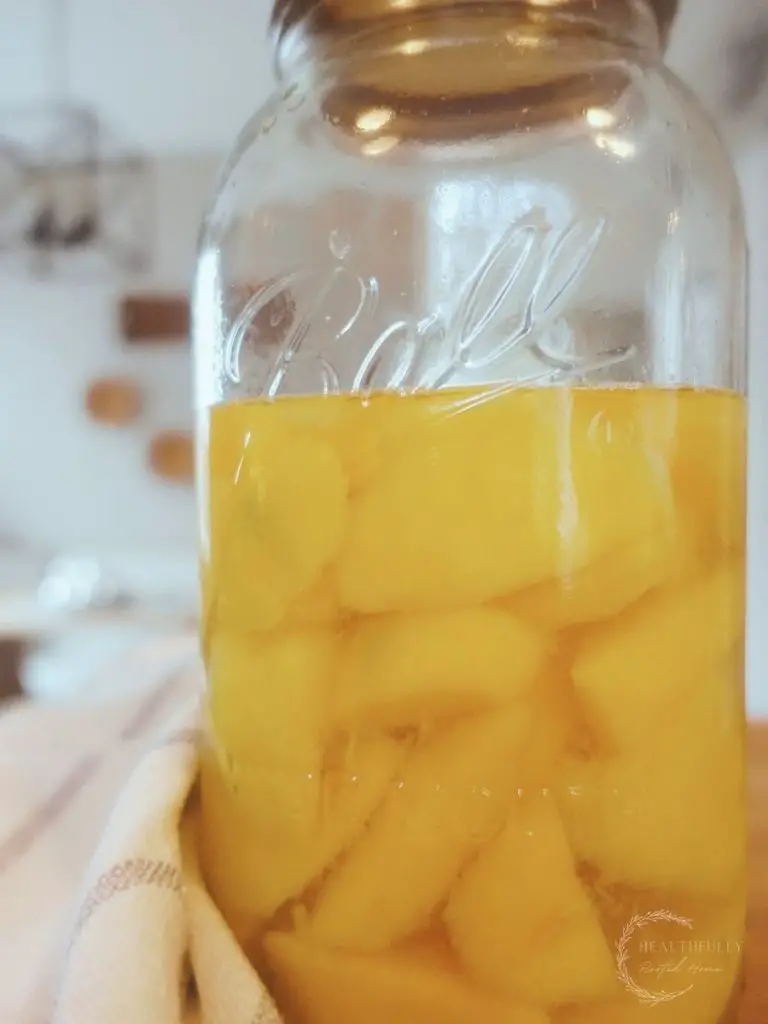 fermented mangos in a mason jar next to a tea towel with baskets on the wall in the background