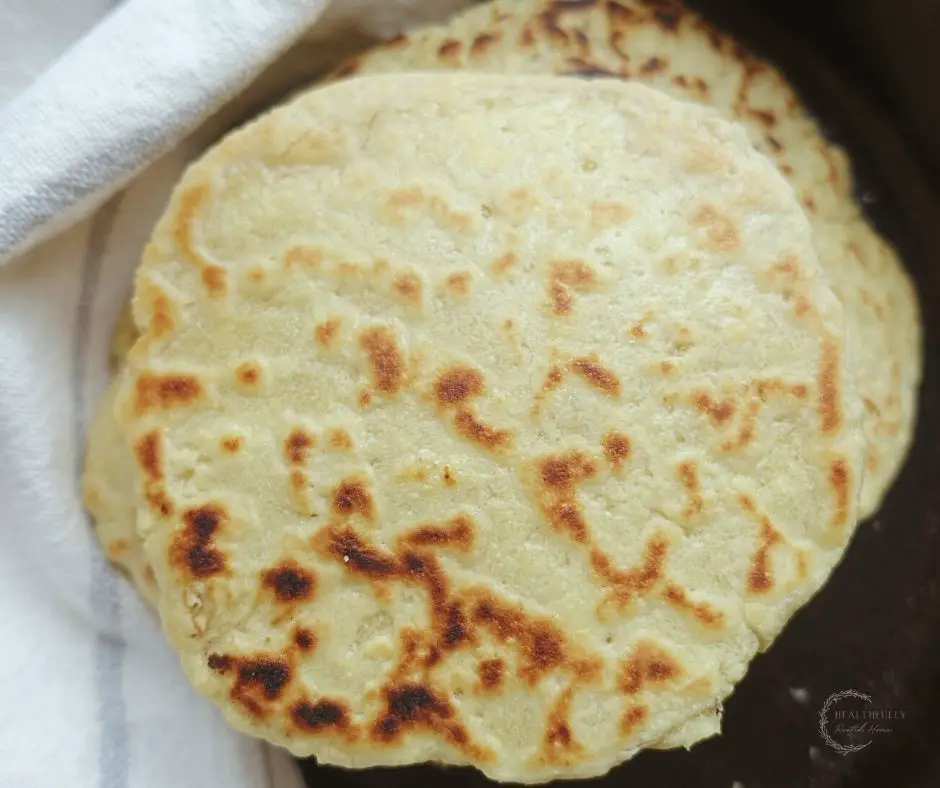 einkorn sourdough tortillas stacked on top of each other in a cast iron skillet 