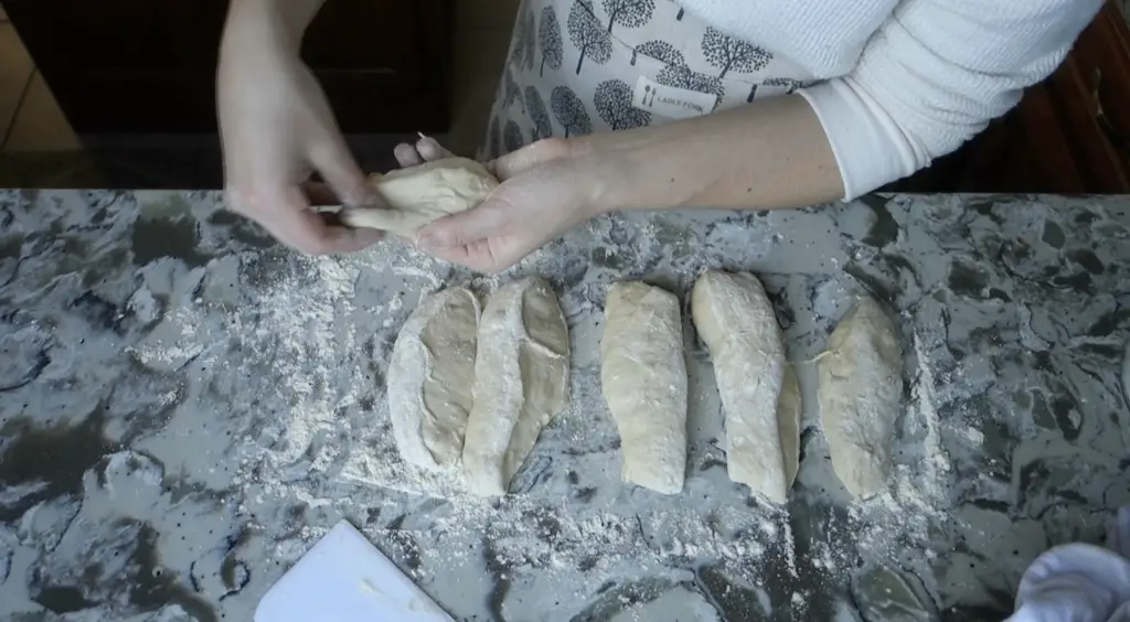 pulling sourdough out to shape into a tight ball of dough with strips of dough beneath it 