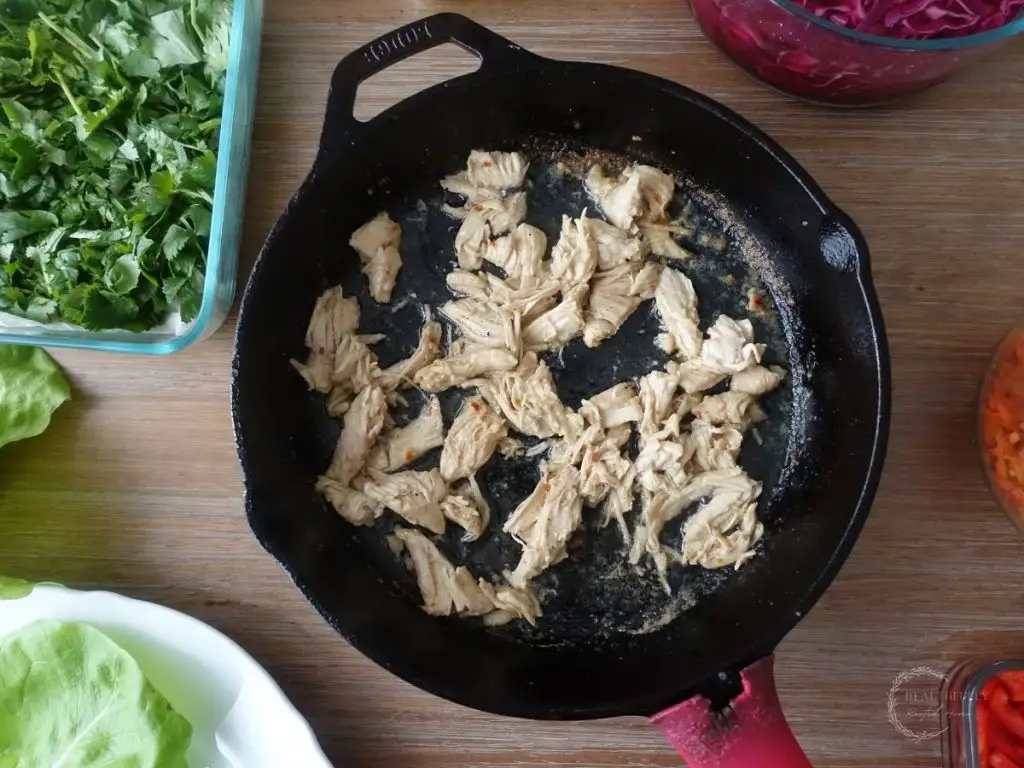 thai coconut lime chicken in a cast iron skillet with a red handle and cilantro on the side