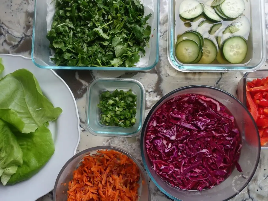 ingredients for lettuce wraps with cilantro pickled cucumbers cabbage green onions carrots and butter lettuce