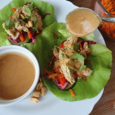 thai coconut lime chicken lettuce wraps with peanut sauce drizzled on top with a silver spoon