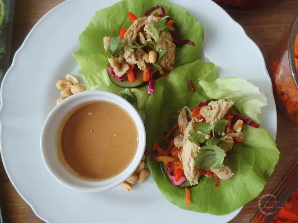 thai coconut lime chicken lettuce wraps with a side of peanut sauce in a white dish