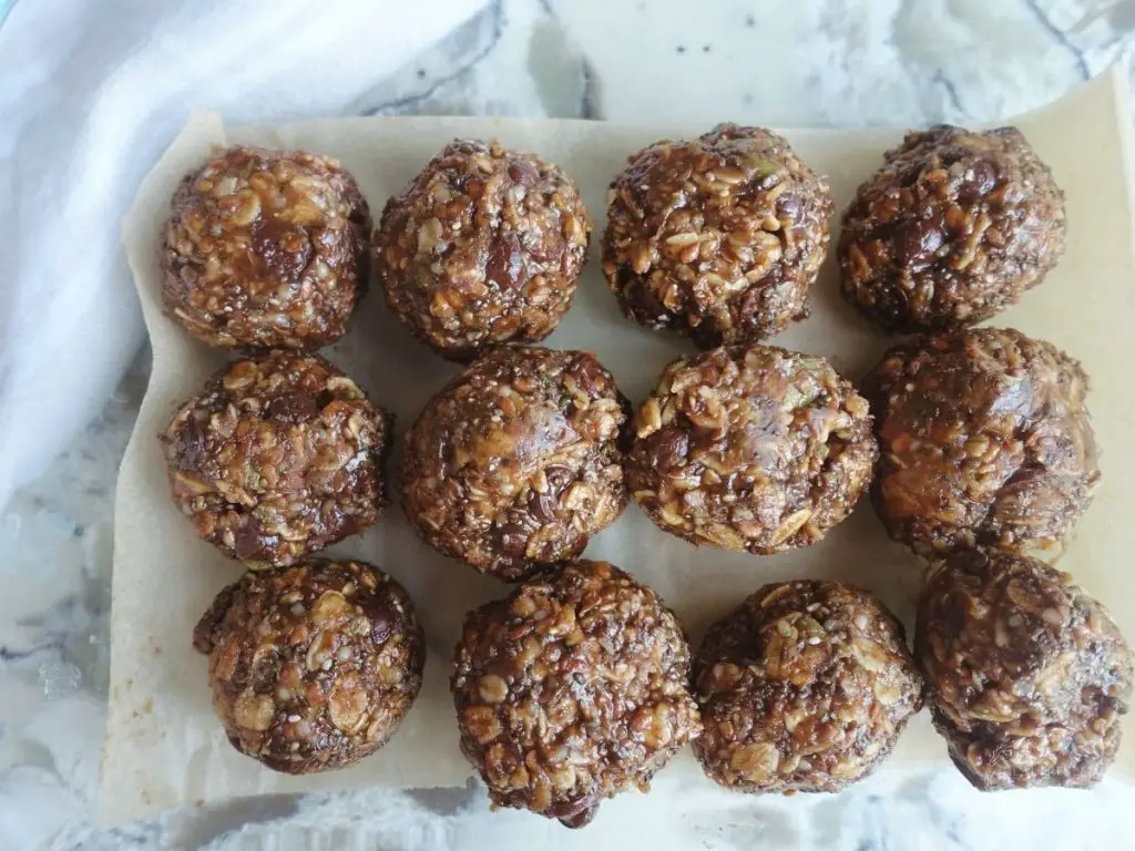 peanut butter bliss balls lined up in rows in a glass dish on top of parchment paper
