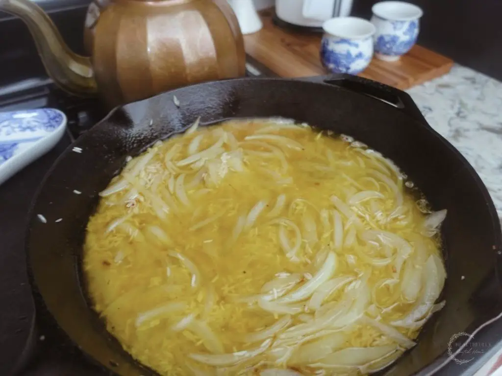 basmati rice soaking up bone broth in a cast iron skillet making risotto