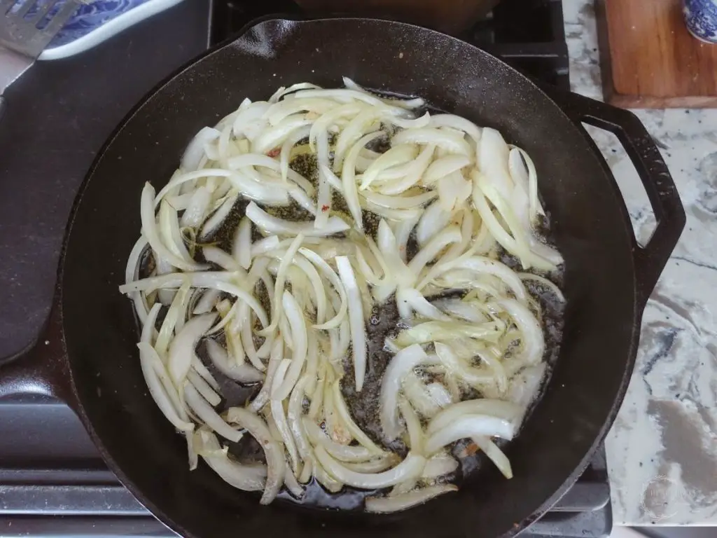 sauteed onions in a cast iron skillet next to a granite countertop