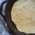 same day sourdough pizza crust in a cast iron skillet with an apron next to it