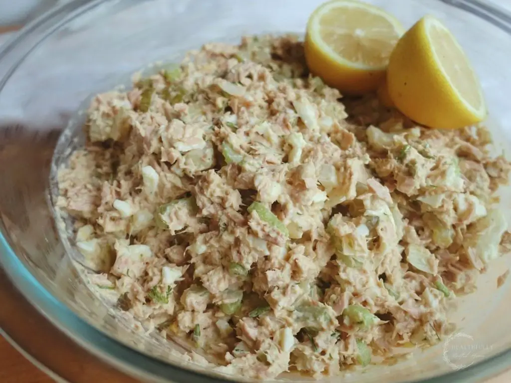 southern tuna salad in a clear bowl with halved lemons as garnish