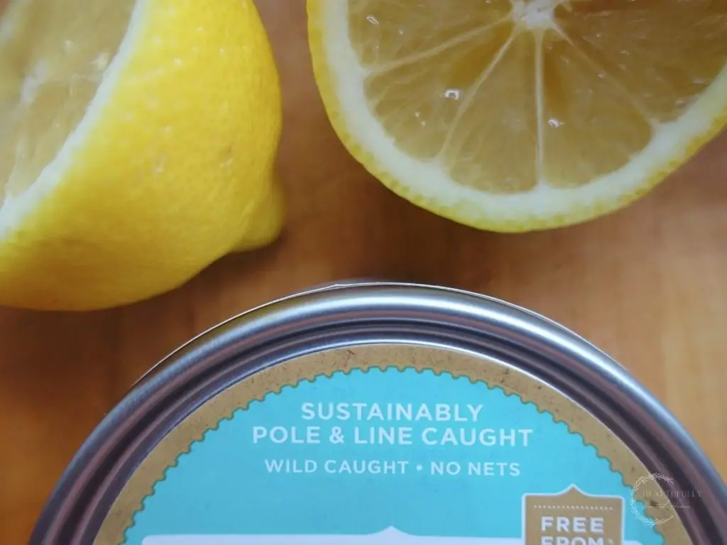 line and pole caught canned tuna with a blue label and halved lemons behind it