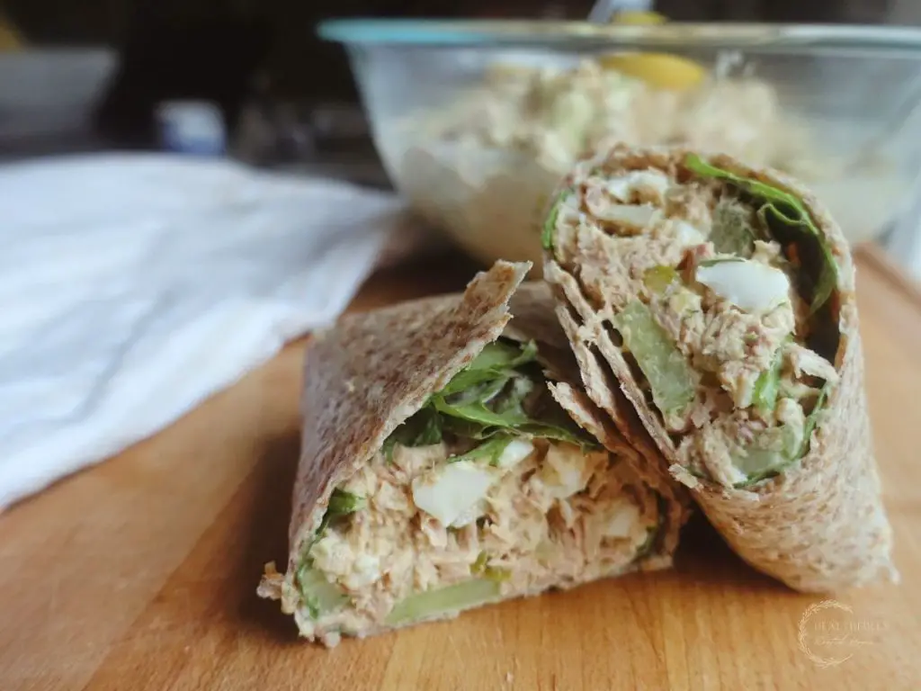 southern tuna salad wrapped in tortillas with a glass bowl of tuna salad behind it and a white tea towel