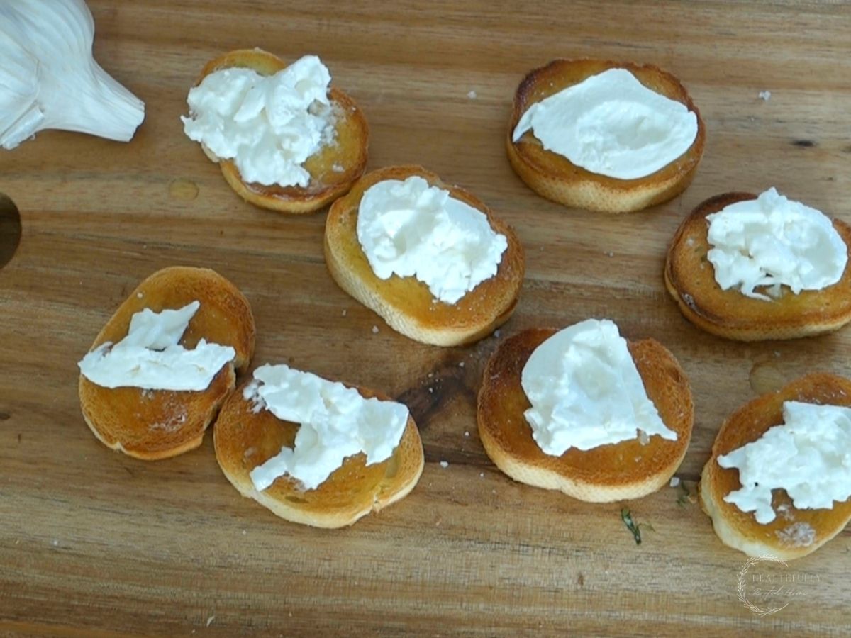 toasted crostini on a wooden cutting board topped with burrata cheese