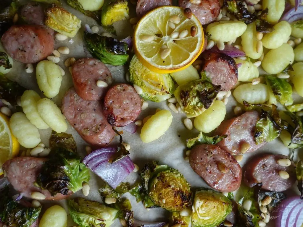 gnocchi sheet pan meal with roasted lemons vegetables gnocchi and chicken apple sausage on a baking sheet
